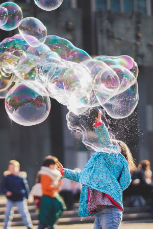 Kids birthday party bubble game. Child with large bubbles.